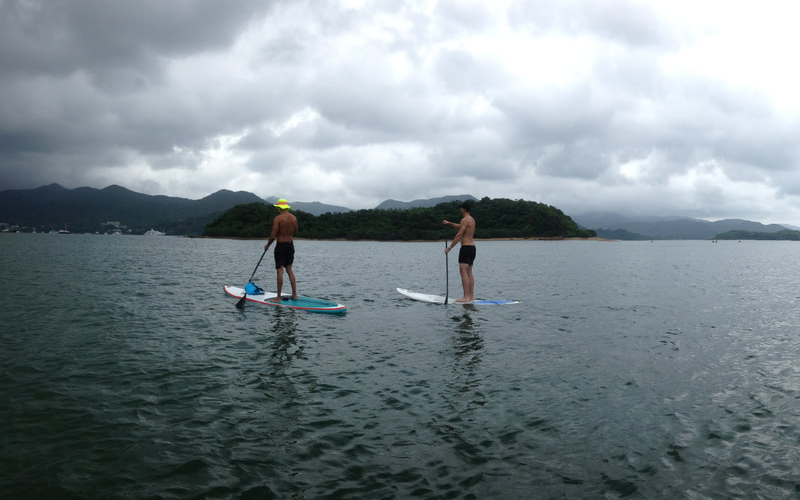 Paddleboarders enjoying calm waters near Hong Kong islands.