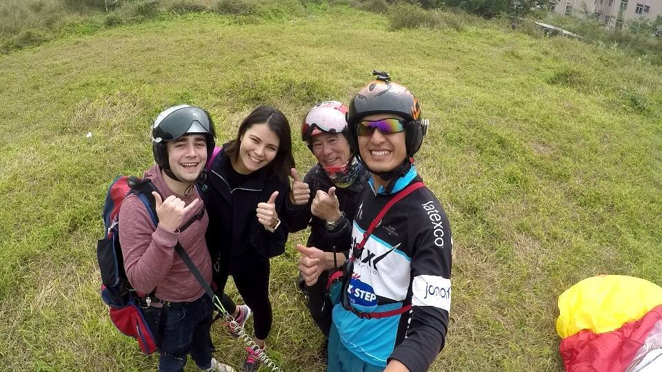 Group of paragliding students and instructor standing on grassy landing field in Hong Kong