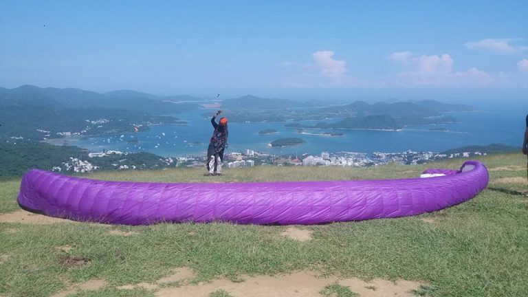 Paragliding pilot preparing a purple wing on a launch site in Hong Kong