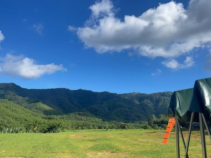 Launch and landing field for tandem paragliding at Luofu Mountain in China near Shenzhen and Guangzhou, with green hills and a blue sky in the background.